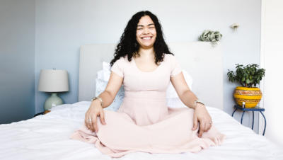 Woman sitting in a pink dress in bed smiling